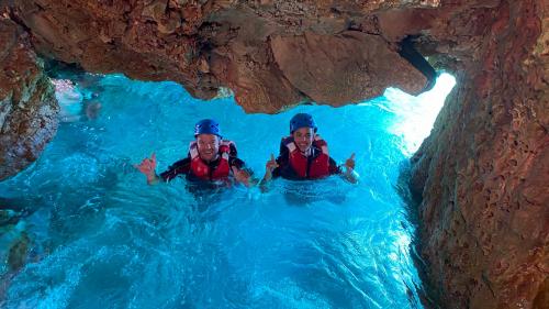 Two hikers in the blue water inside a cave