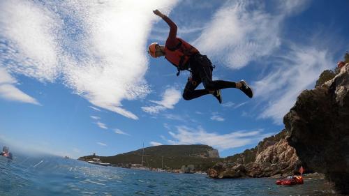 A boy dives into the water of Cala Dragunara