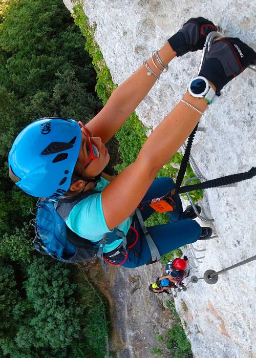 Giovane donna sale lungo la scala d'acciaio nella roccia