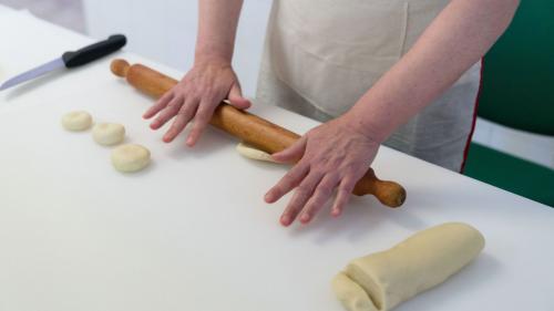 Le cuisinier étale la pâte à panadas à l'aide d'un rouleau à pâtisserie