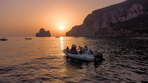 Il sole tramonta tra Pan di Zucchero e la costa di Masua durante una gita in gommone