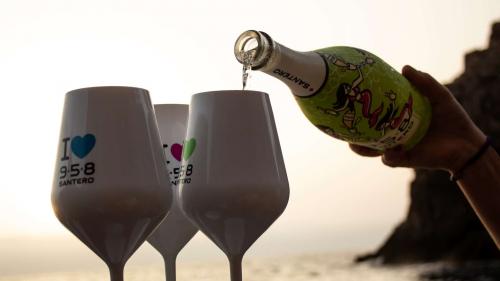 Crew member pours wine into glasses during dinghy sunset excursion in Porto Flavia