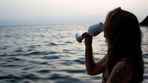 Ein Mädchen trinkt ein Glas Wein an Bord eines Schlauchboots während eines Ausflugs bei Sonnenuntergang