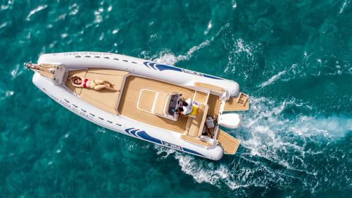 Gommone ripreso dall'alto naviga nel mare azzurro del sud-ovest della Sardegna