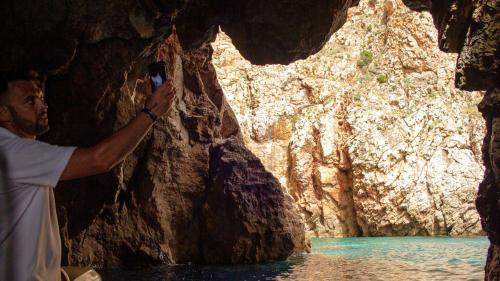 Visita della Grotta Azzurra durante un'escursione in gommone nella costa sud-ovest della Sardegna al tramonto