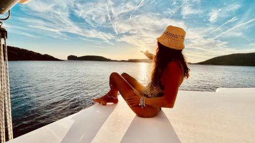 Chica se divierte en catamarán durante una excursión al atardecer en Porto Conte