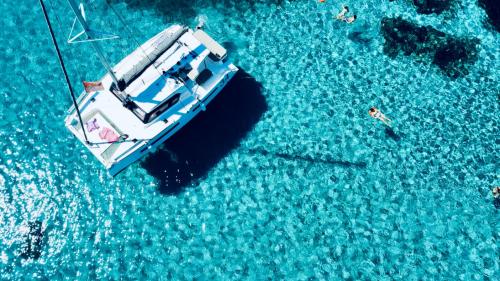 Catamaran stops while hikers swim in the azure waters of Fornelli pools