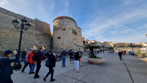 A group of people walk through the historic center of Alghero
