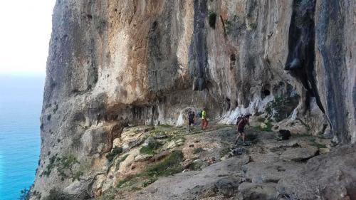Escursionisti affrontano un passaggio a fianco a una parete di roccia