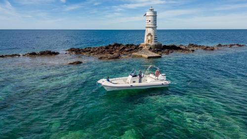 Shared dinghy sails in front of the Mangiabarche Lighthouse
