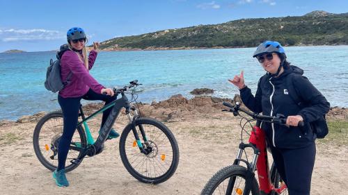 Zwei Mädchen lächeln während einer Tour mit dem Elektrofahrrad an der Costa Smeralda