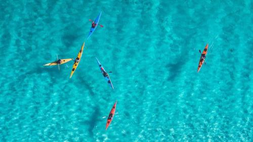 Kayaks sail in the blue sea of the Gulf of Asinara