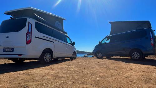 Two camper vans stop at a coastline in Sardinia