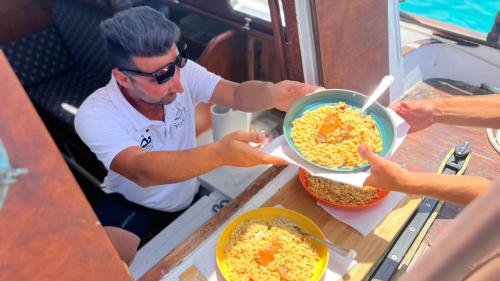 Le skipper sert des plats à base de fregula sarda et de fruits de mer.