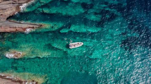 Gommone sosta a largo della costa rocciosa di Masua