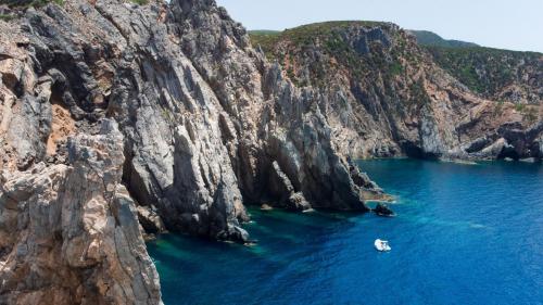 Una lancha neumática se detiene cerca de la costa rocosa de Iglesias