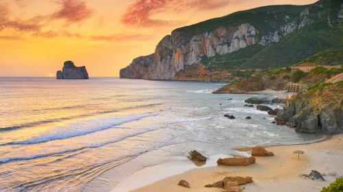 Masua beach with a view of Sugarloaf Mountain at sunset