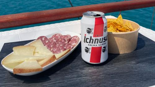 Queso, salchichas y cerveza servidos a bordo del velero en Carloforte