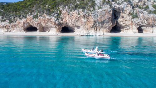 Des bateaux gonflables naviguent à Cala Luna devant les grottes de Bue Marino