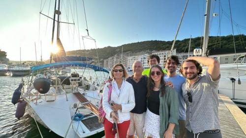 Gruppo di persone vicino alla barca a vela nel golfo di Alghero