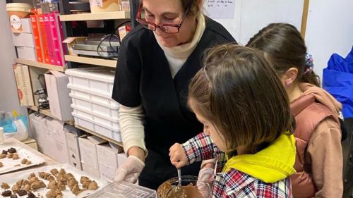 Bambini durante preparazione divertente del cioccolato in azienda a Laconi con guida e produttrice locale