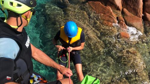 Un garçon équipé fait de l'escalade guidée dans la mer bleue du centre-est de la Sardaigne.