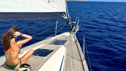 Ragazza a bordo di una barca a vela ammira il mare blu di Cagliari