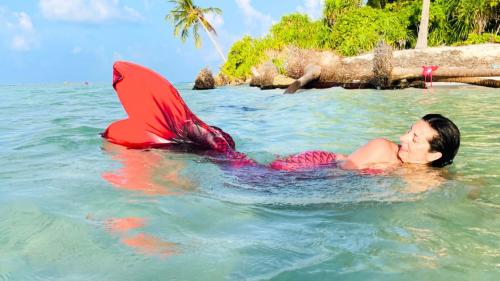Une jeune fille déguisée en sirène nage dans la mer cristalline de Cagliari