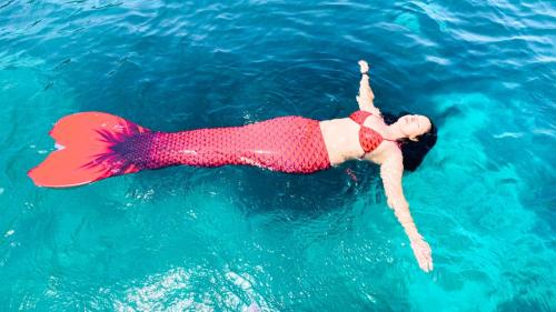 Une jeune fille déguisée en sirène nage dans la mer cristalline de Cagliari