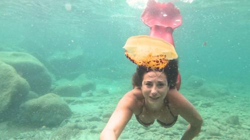 Une sirène nage sous l'eau dans la mer de Cagliari avec une méduse