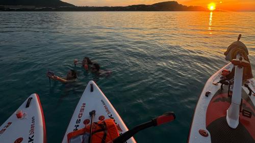 Bici d'acqua e persone durante il tramonto nelle acque della Pelosa