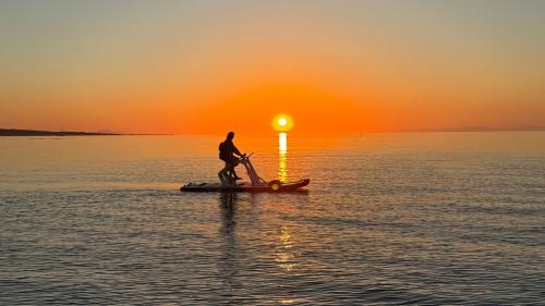 Persona pedalando sull''acqua al tramonto a Stintino