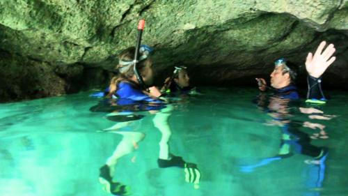 Guía con excursionistas con equipo de snorkel en el interior de una cueva sólo accesible por mar 