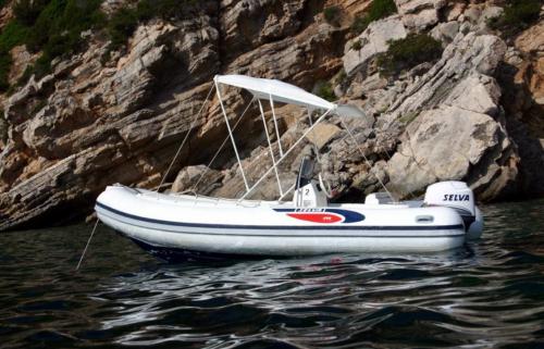 Schlauchboot mit Markise im Wasser von Alghero verankert