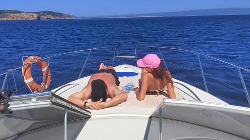 Gente en la proa durante la excursión en barco por la costa de Alghero
