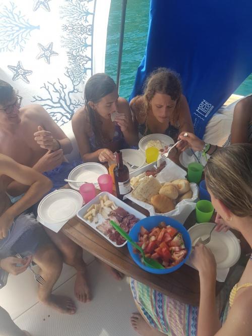 Jungen und Mädchen essen an Bord eines Bootes an der Küste von Alghero