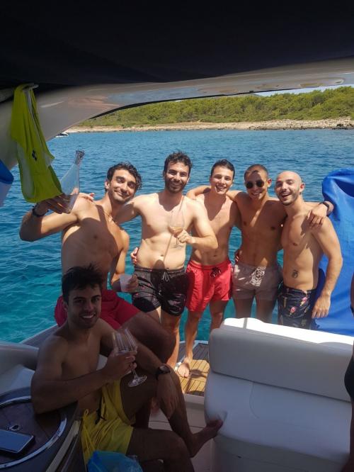 Guys celebrate aboard a boat in Alghero
