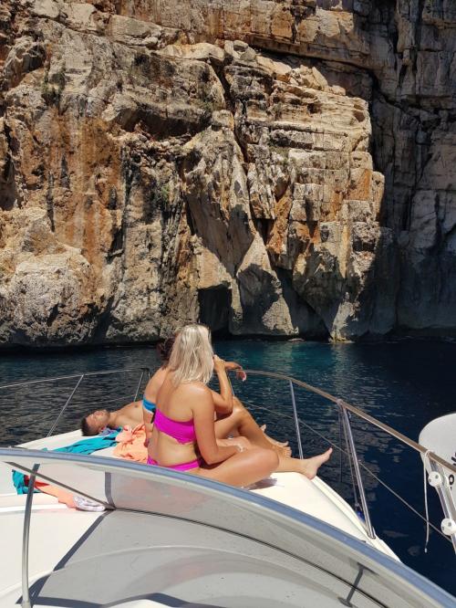 Menschen, die während des Bootsausflugs an der Küste von Alghero im Bug ein Sonnenbad nehmen