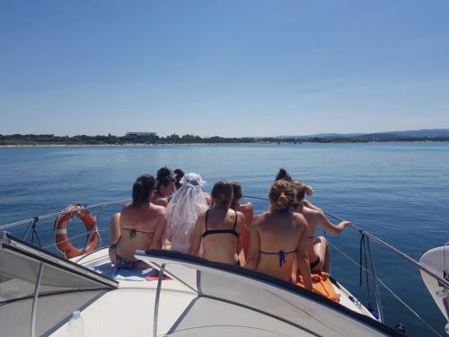 Gente en la proa durante la excursión en barco por la costa de Alghero