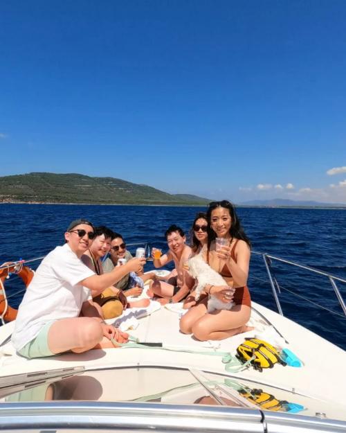 Gente en la proa durante la excursión en barco por la costa de Alghero