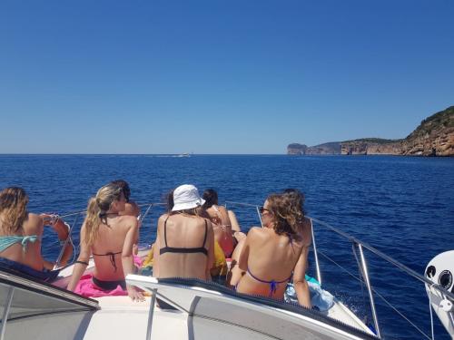 Gente en la proa durante la excursión en barco por la costa de Alghero