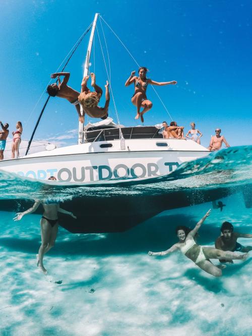 Group of friends aboard a catamaran dive and have fun