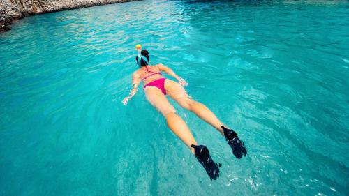 Chica haciendo snorkel en el agua azul en Bosa
