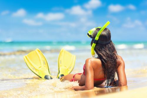 Mädchen am Strand mit Maske und Flossen