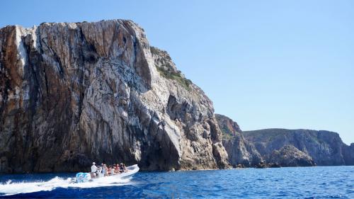 Schlauchboot segelt in der Nähe eines Stapels an der Südwestküste Sardiniens