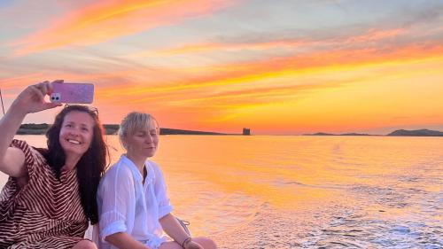 Due amiche fanno una foto col tramonto sul mare
