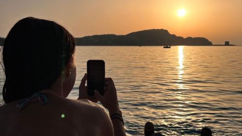 Una ragazza scatta una foto del tramonto a La Pelosa