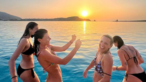 Quattro amiche scherzano sul catamarano a La Pelosa al tramonto