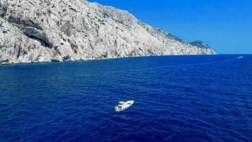 The boat sails through the blue sea of the Tavolara coastline