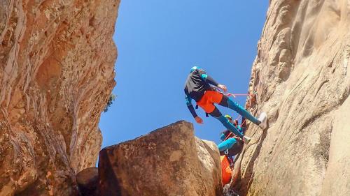 Un excursionista desciende en rápel por la pared del cañón